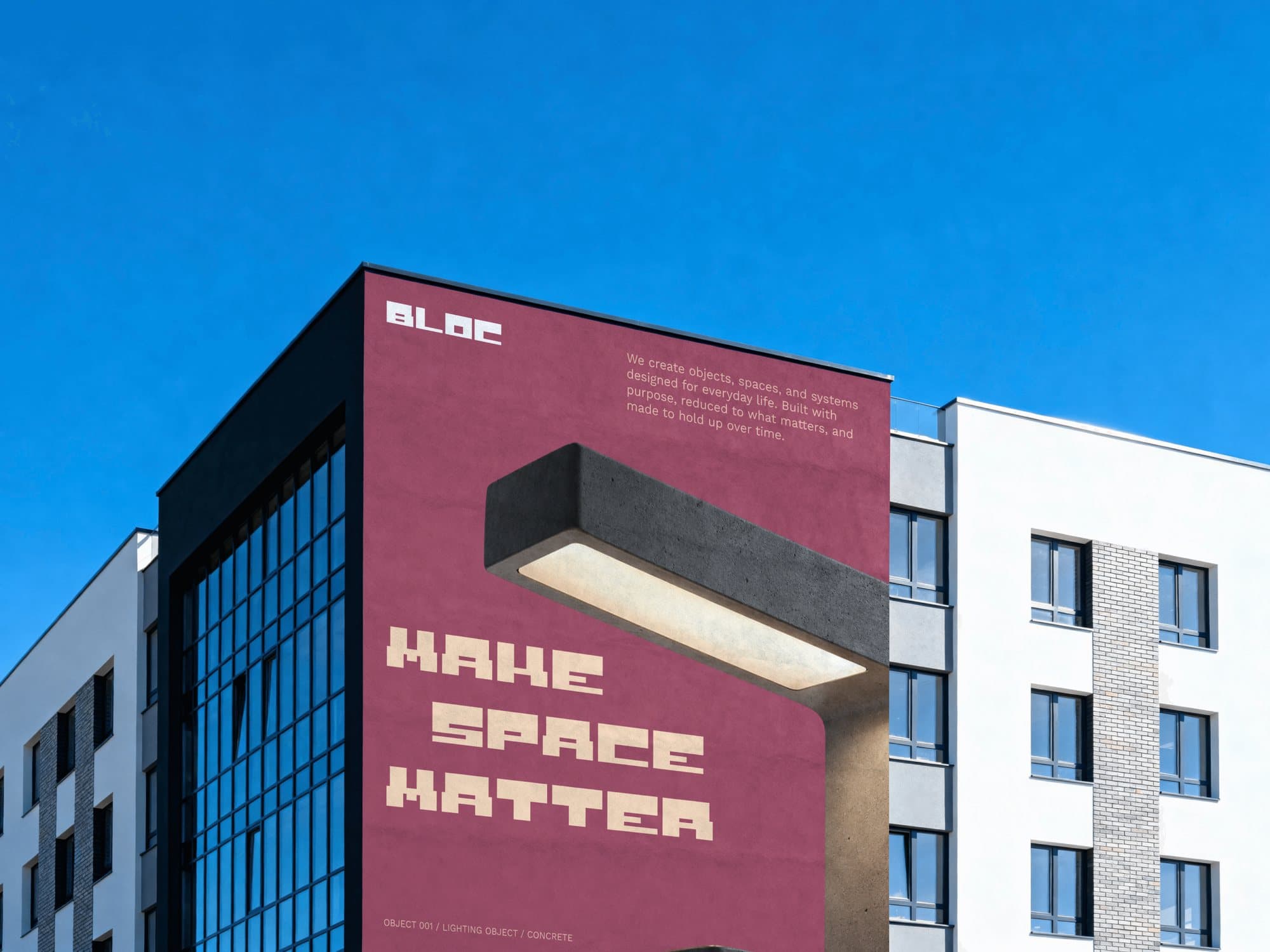 Building with a rose-coloured wall: BLOC set small at the top and MAKE SPACE MATTER stacked large in peach Riteblock, beside a concrete lamp hanging off the facade.